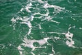 Turquoise green seawater with sea foam as background, close up. Surface of sea with waves, splash, foam and bubbles. Royalty Free Stock Photo