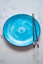 Turquoise hand painted ceramic serving plate with wooden chopsticks on side Royalty Free Stock Photo