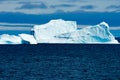 Huge Iceberg with escarpment shining turquoise on grey day in Greenland