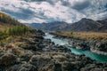 Turquoise Katun river in gorge is surrounded by high mountains under majestic autumn sky. A stormy mountain stream