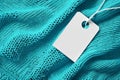 Turquoise knit fabric with white clothing tag, representing sales