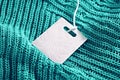 Turquoise knit fabric with white clothing tag, representing sales