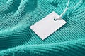 Turquoise knit fabric with white clothing tag, representing sales