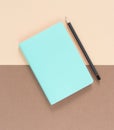 Turquoise notepad and blac pensil on brown background. Working place. Space for notes. Top view.