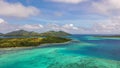 Turquoise ocean waters under the clouds. Mountains in the distance. Drone view of the Fiji Islands