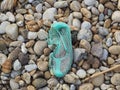 Turquoise old bathing shoe on pebble beach Royalty Free Stock Photo