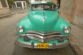 Turquoise old Dodge parked in front of old buildings in Havana, Cuba