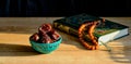 Turquoise piala with traditional oriental pattern with dates and green and gilded book of Quran on table during sunset First meal