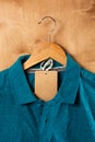 Turquoise polo shirt on wooden hangers with a brown tag. wooden background Royalty Free Stock Photo