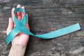 Turquoise Robin egg blue ribbon on human hand old aged background raising awareness on Bone tumor, Addiction recovery