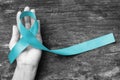 Turquoise or Robin egg blue ribbon on human hand old aged background raising awareness on Bone tumor, Addiction recovery