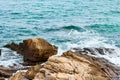 Turquoise rolling wave slamming on the rocks of the coastline