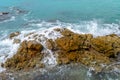 Turquoise sea water crashing on rocks on sunny summer day. Royalty Free Stock Photo