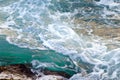 Turquoise sea water hits stony shore. Natural background.