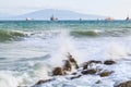 Turquoise sea waves break against stones on background of ships anchored on the horizon during a storm Royalty Free Stock Photo