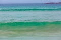 Turquoise small ocean waves near beach.