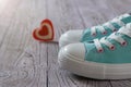 Turquoise sneakers and a red and white heart on the wooden floor. Royalty Free Stock Photo