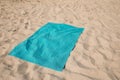 Turquoise soft beach towel on sunlit sand