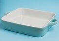 Turquoise square ceramic baking dish on a blue background Royalty Free Stock Photo