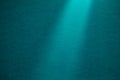 Turquoise vertical ray of light on a dark turquoise fine-textured background
