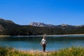 Turquoise water of the lake, pine forest and mountains. Stunning background with nature tourist girl rejoicing on the beach