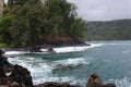 Gorgeous blue water of the Pacific Ocean flowing into a rocky cove lined with tropical rainforest in Haiku, Maui, Hawaii