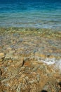 Turquoise water on stoney beach.