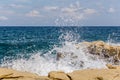 Turquoise wave breaks on rocks