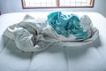 Turquoise and White crumpled bed sheet on white bed, Selective focus, Bedroom cleaning concept