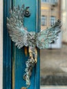 Turquoise wooden and glass entrance with antique door handle in the form of a bird. Unusual details of ornate door