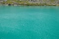 Turquose water texture and bank of the Akchan lake in the Altai mountains, Russia