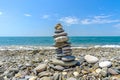 Turret made of oval sea stones. Sea surf line against the blue sky on a sunny summer day. Royalty Free Stock Photo