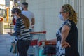 A sad woman with face mask stands with shopping cart,waits to buy food during pandemic covid19