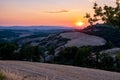 Tuscany landscape with grain fields, cypress trees and houses on the hills at sunset. Summer rural landscape with curved Royalty Free Stock Photo