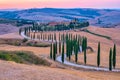 Tuscany landscape with grain fields, cypress trees and houses on the hills at sunset. Summer rural landscape with curved Royalty Free Stock Photo