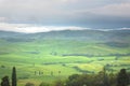 Tuscany, rural landscape. Countryside farm, cypresses trees, green field, cloudy day Royalty Free Stock Photo