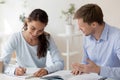 Tutor helping female student making notes with research work