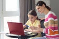 A tutor helps a girl learn online through the Internet