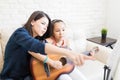 Tutor Showing Musical Notes To Girl Playing Guitar