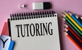 TUTORING - a word written in a notebook on a pink background and colored pencils Royalty Free Stock Photo