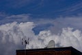 TV antenna, satellite dish on blue cloudy sky background.