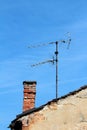 TV antennas next to red bricks chimney on top of old dilapidated house with cracked bricks and fallen parts of facade Royalty Free Stock Photo