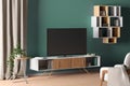 TV on the cabinet in modern living room on turquoise wall background