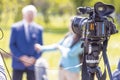 TV camera in focus, blurred female journalist making TV interview at press, news conference or media event