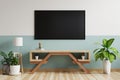 TV on the green-white wall in the living room is decorated with a TV cabinet with a lamp and plant pots on the wooden floor.3d