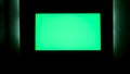 TV with horizontal green screen on a black wall with green illumination. Concept. Close up of chroma key TV screen in a