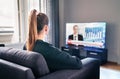 Tv news. Woman watching television broadcast in home living room. Reporter, anchor and studio host in screen with newscast. Royalty Free Stock Photo