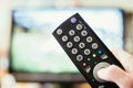 Male hand is holding TV remote control, streaming on a smart TV Royalty Free Stock Photo