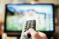 Male hand is holding TV remote control, streaming on a smart TV Royalty Free Stock Photo