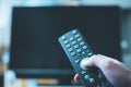 Male hand is holding TV remote control, streaming on a smart TV Royalty Free Stock Photo